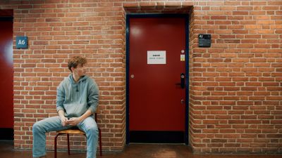 Elev venter ved eksamenslokalet
